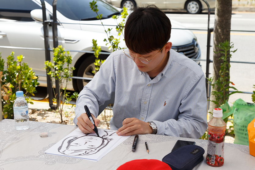 캐리커쳐를 그리고 있는 봉사자 사진