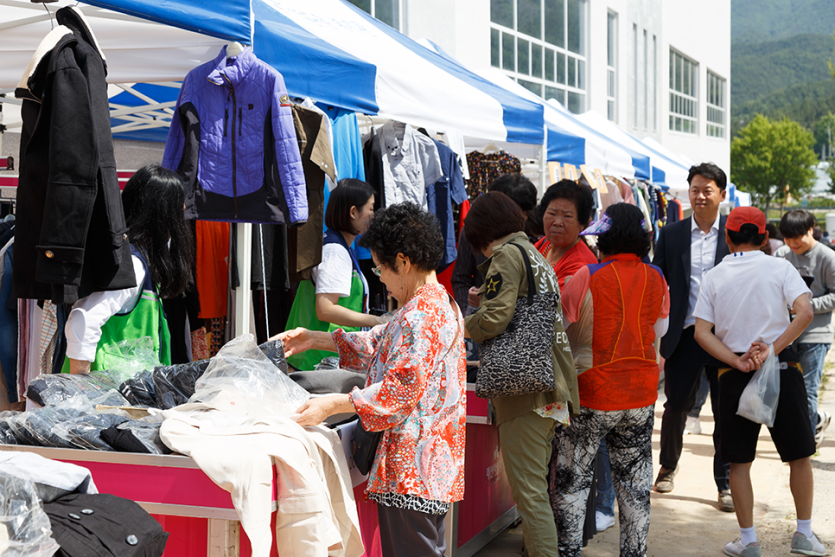 바자회에서 옷을 판매하는 부스와 옷을 구경하고있는 이용자들 사진