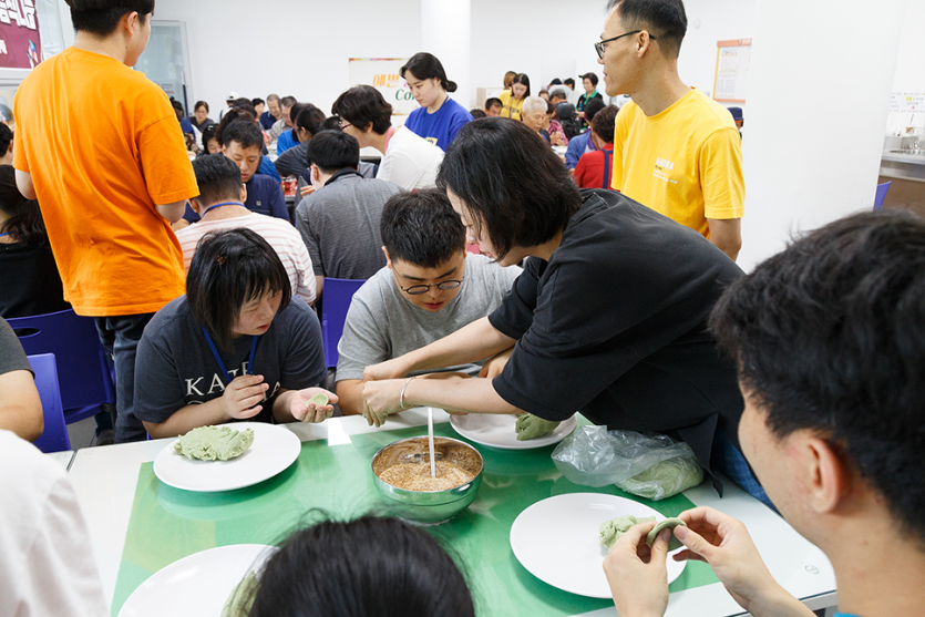 송편빚기를 도와주고있는 봉사자와 송편을 빚고있는 복지관이용자들 사진