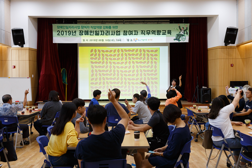 직무역량교육 중 손을 들고있는 강사와 교육생들 사진