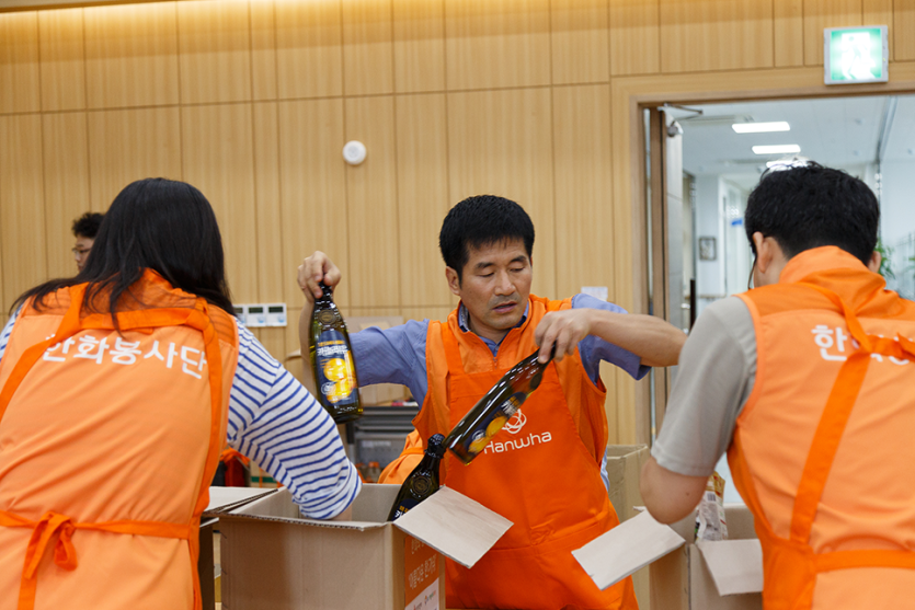 카놀라유를 박스에 옮겨담고있는 봉사자들의 사진