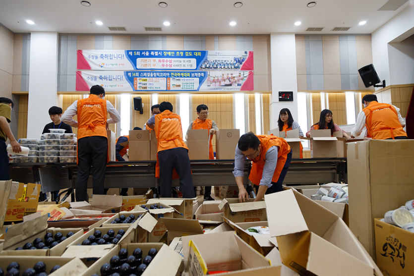 박스에 포장되어있는 물품들과 포장을 하고 있는 봉사자들 사진