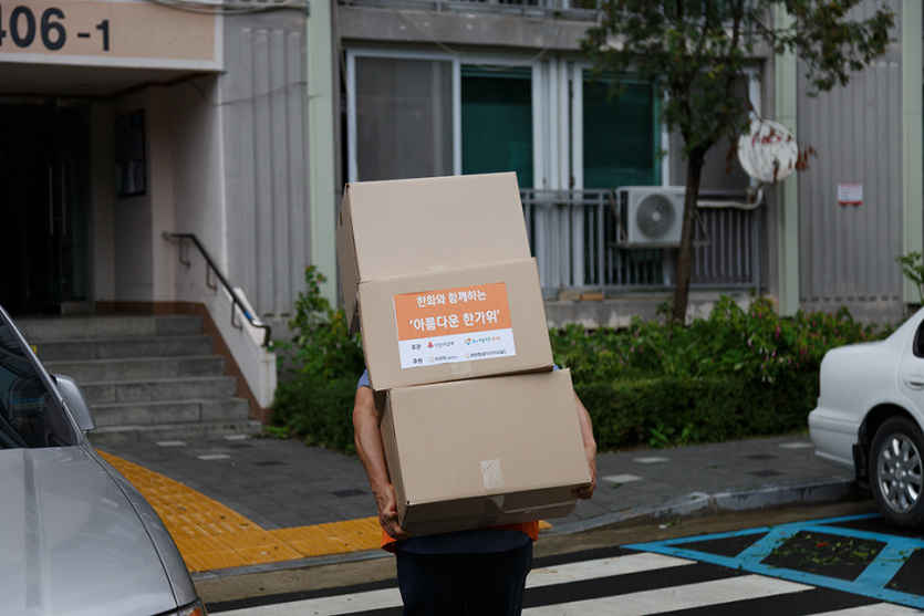물품을 등에 짊어지고 배송하고있는 봉사자의 뒷모습 사진