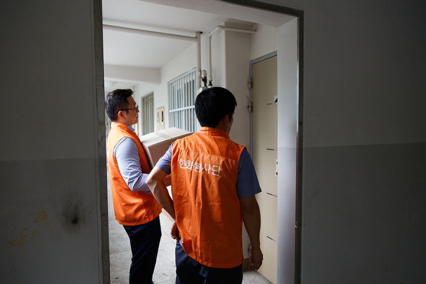 문앞에서 물품을 들고 기다리고있는 봉사자들 사진